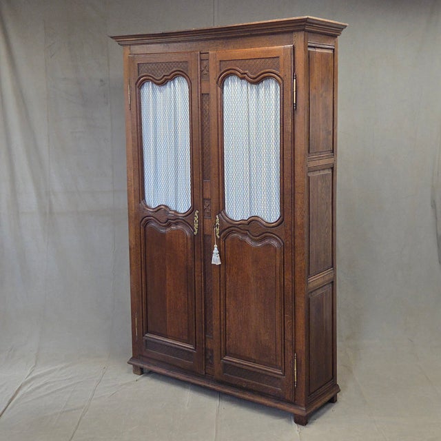 A gorgeous and functional antique 19th century French provincial oak wardrobe cabinet that features carved designs on the...
