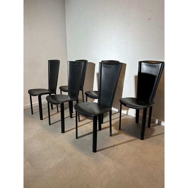 Elegant set of six vintage dining chairs upholstered in black leather. The design is defined by the tall, slightly tapered...