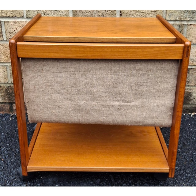 A Mid Century Scandinavian Modern Magazine Rack Rolling Tiered Side Table Measures 19.5" in width, 17" in depth and 20" in...