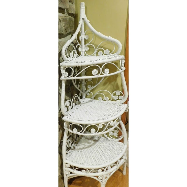 This vintage 1960s white wicker corner étagère is a true standout, blending ornate heart and scrollwork motifs with...