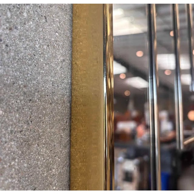 A stunning postmodern geometric mirror featuring a layered, dimensional design with a warm brass-gold trim. This...