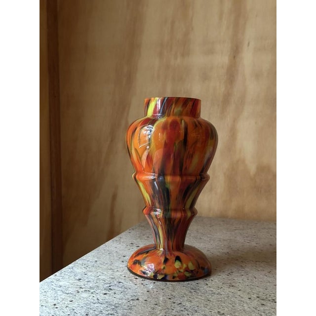 This Antique Bohemian Kralik baluster vase is a striking example of multicolored splatter glass, executed in the...