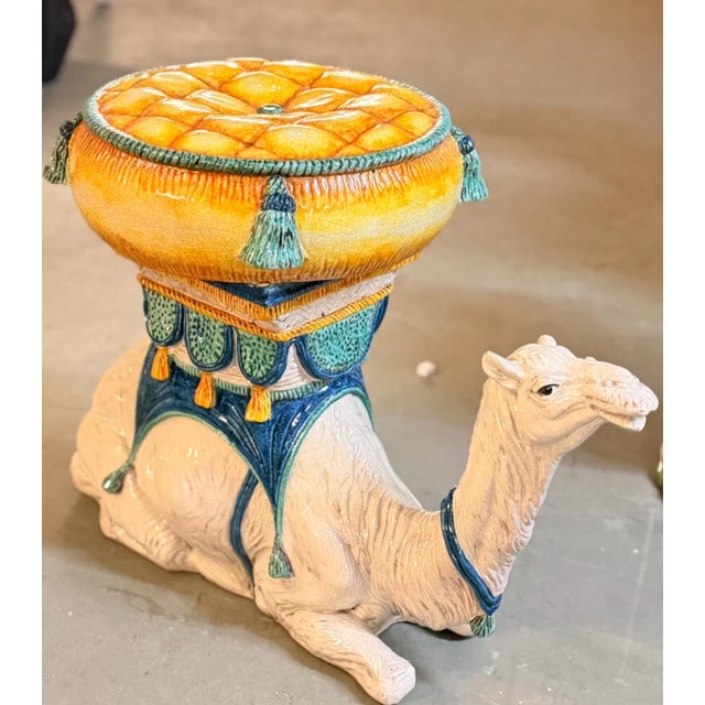 A show-stopping ceramic garden seat from Italy, sculpted in the form of a resting camel rendered in a rich ivory glaze...