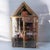 This is a gold-trimmed glass curio cabinet featuring a house-shaped roof and a latching door.This 2-tier display case is...