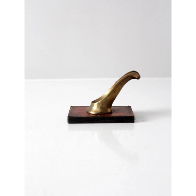 This is a vintage pipe rest. The Italian made tobacciana stand features a brass pipe holder with stamped leather base.