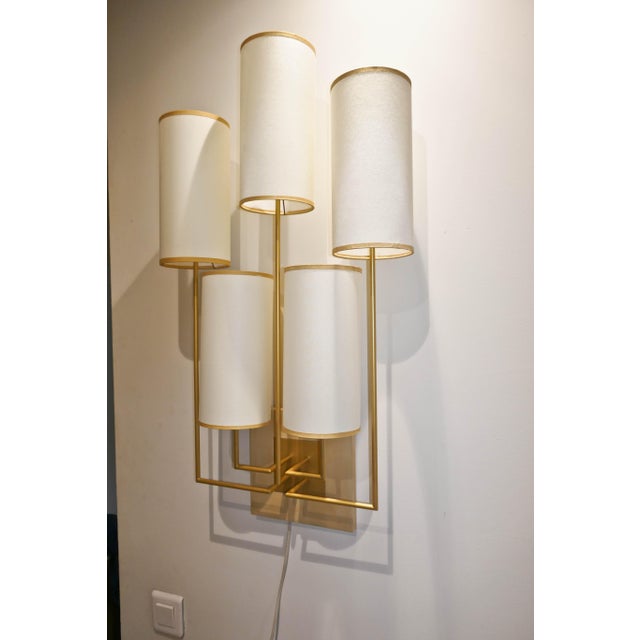 Pair of wall sconces in patinated gold metal, with sycamore bases. The lampshades are white fabric with gold trim. They...