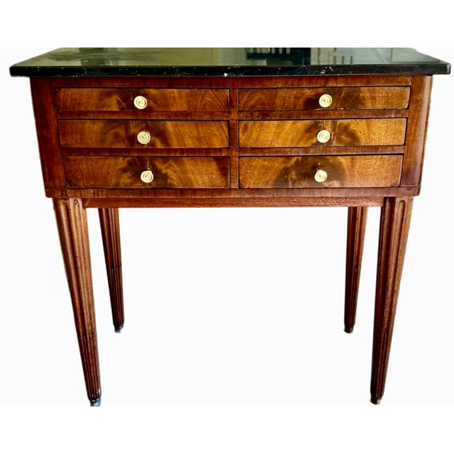 An unusual Directoire commode with 6 drawers and fluted legs terminating in brass capped feet. Black and white marble top....