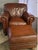 Italian-crafted Natuzzi Maturità armchair and matching ottoman upholstered in rich cognac protected top grain leather....