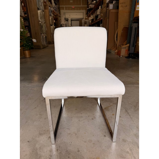 Contemporary dining chair featuring a sleek, minimalist silhouette with clean lines and tailored upholstery. Wrapped in a...