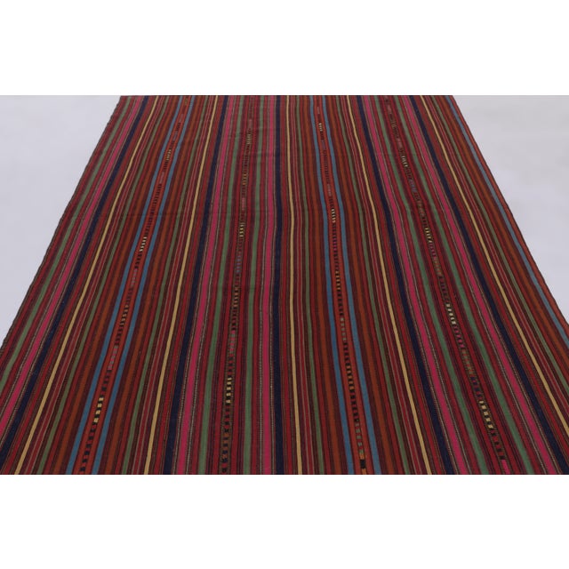 Made with handwoven wool circa 1950-1960, this 7x8 vintage flat-weave Kilim is a particularly colorful and sought-after...