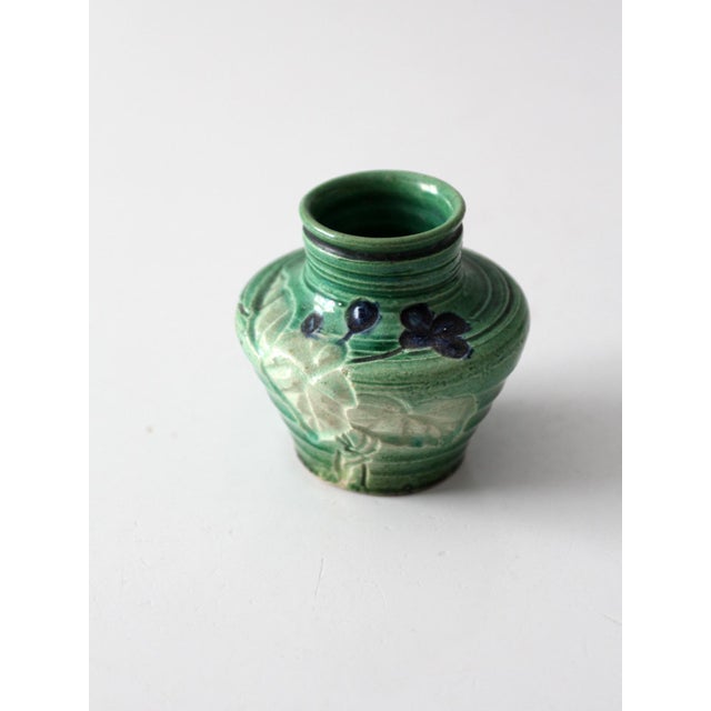 This small vintage art pottery vase features a sculptural baluster form, molded botanical relief, and a rich green glaze...