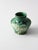 This small vintage art pottery vase features a sculptural baluster form, molded botanical relief, and a rich green glaze...