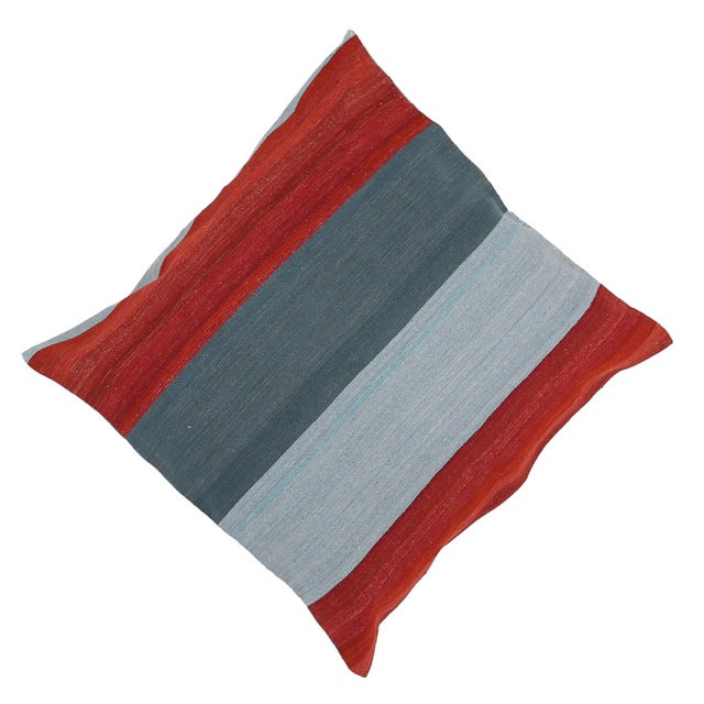 A one-of-a-kind handwoven wool kilim floor pillow featuring bold red and teal vertical color-blocks. Fully reversible —...