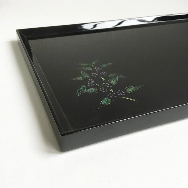 This is a black lacquer tray that features an etched leaf and berry design in the corner. The tray is signed on the back...