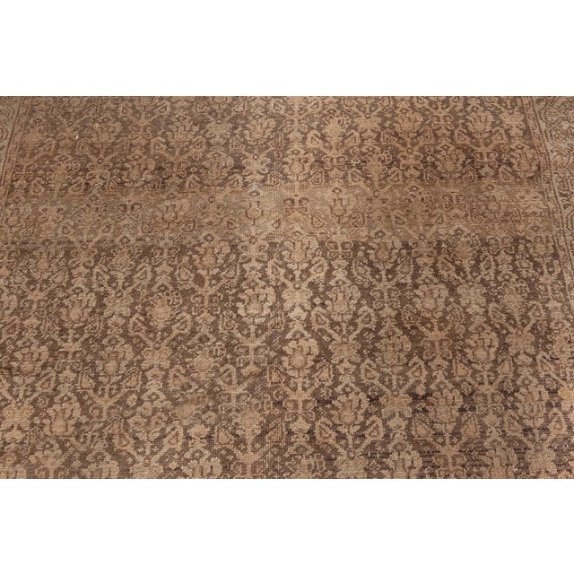 An Antique Persian Malayer Rug with an allover abstract floral and vine design on an abrashed field of brown and taupe....