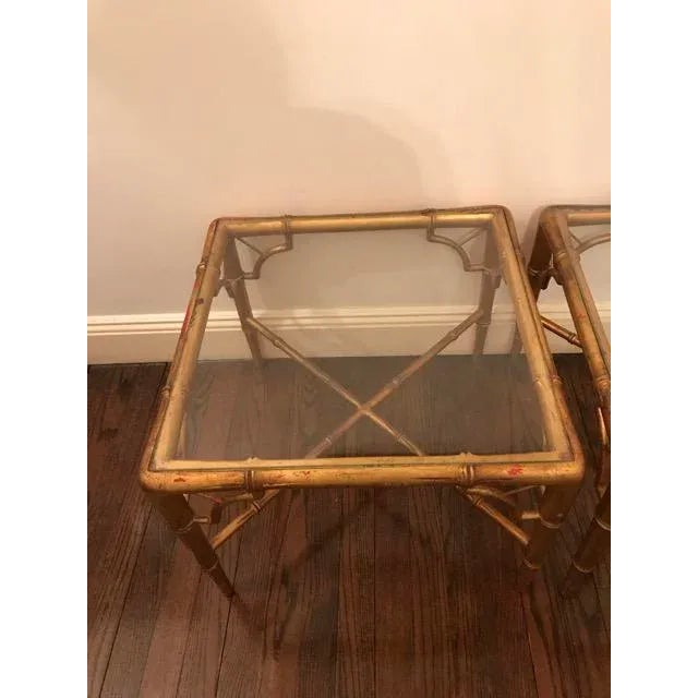 Beautiful pair of Hollywood Regency faux bamboo glass top tables. They are carved wood that have been gold gilted with...