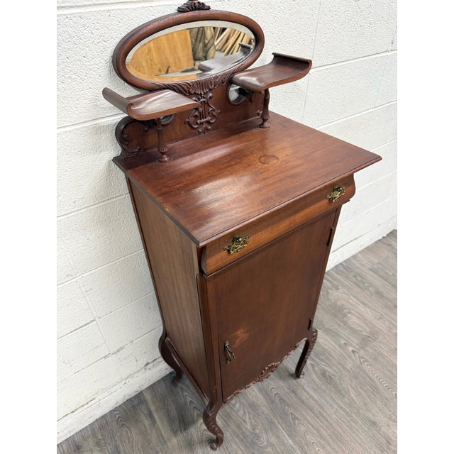 This is an elegant antique Victorian Rococo Revival music cabinet crafted in richly toned mahogany with graceful...