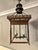 A square bronze lantern with four panes of glass to sides and roof, with petal shaped smoke outlet, pierced filigree work...