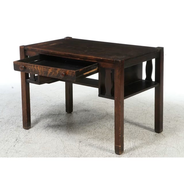 This antique writing desk features classic Arts and Crafts styling. Crafted from solid oak, the piece has a flat...