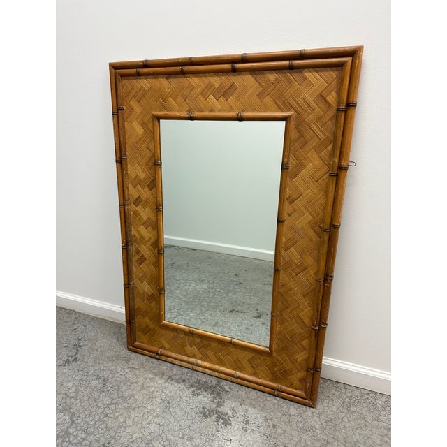 A fabulous vintage hollywood regency wall mirror. A parquet rattan frame with a carved bamboo trim.