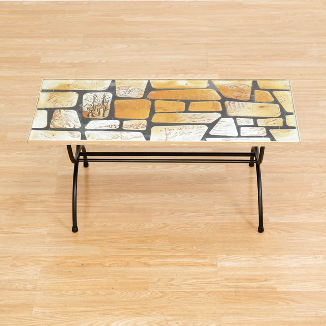 A unique Mid-century glass topped coffee table with mosaic foiled design and funky dancing figures, reminiscent of...
