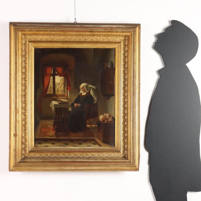 Oil on canvas. Signed lower right. In a soberly furnished room, an elderly woman sits reading, or perhaps meditating, with...