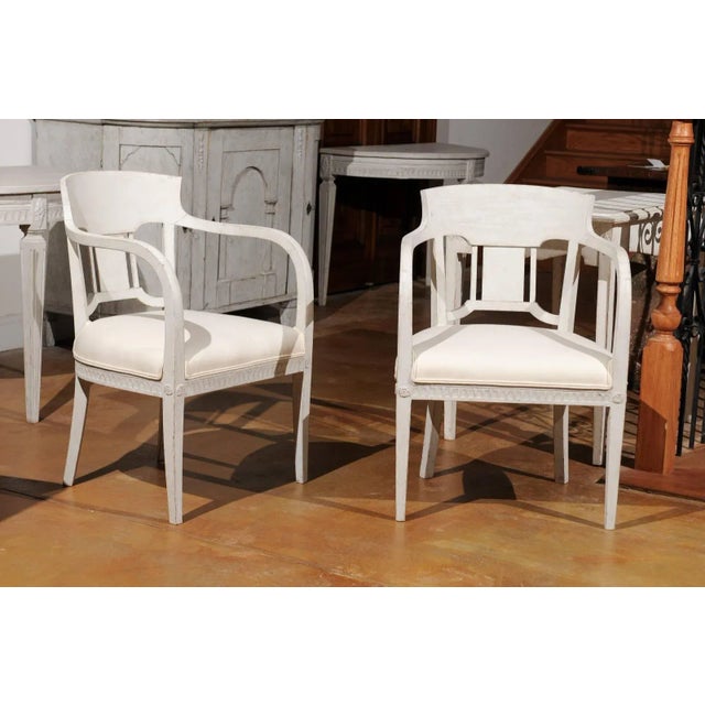 A pair of Swedish painted wood Neoclassical style armchairs from the second half of the 19th century with tall open...