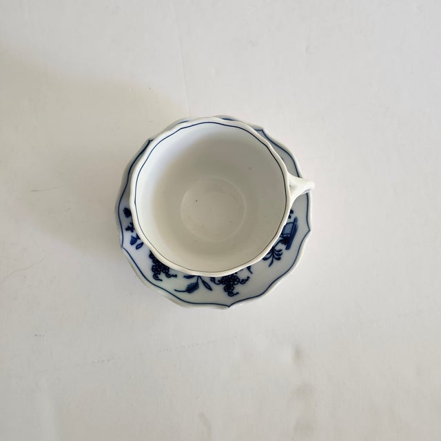 A cup and saucer set by Carl Teichert. The pattern is Blue Onion and features a white background with floral design. It...