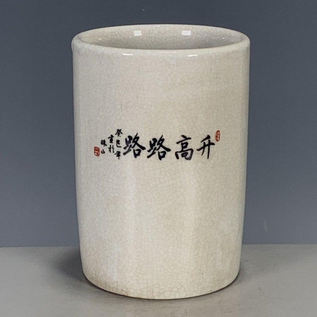 A charming Chinese porcelain brush pot (bitong). The cylindrical vessel features a creamy, all-over crackle glaze and is...