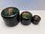 Beautiful vintage set of three nesting round lacquer trinket boxes in a glossy black finish, each topped with a vibrant...