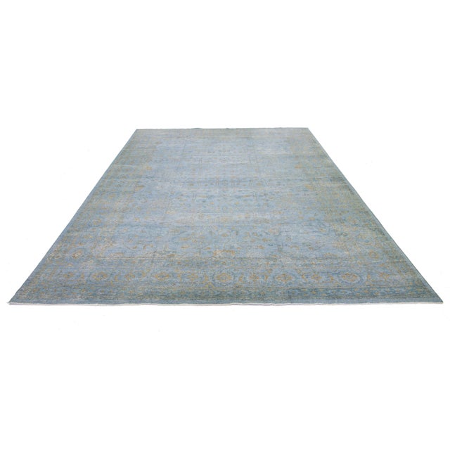 This Oushak rug is hand-knotted with a blue field. This mid-century modern-style rug has an all-over golden floral design....
