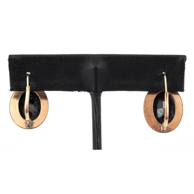 14K yellow gold and black Onyx earrings, featuring two bezel set oval faceted black onyx gemstones, weighing a total of...