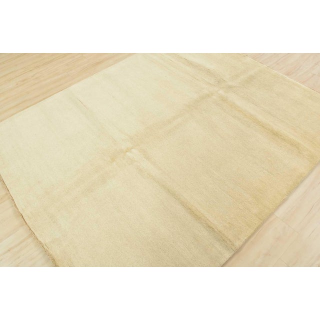 This contemporary solid ivory area rug is hand-knotted with an all-wool pile on a cotton foundation. This rug is new and...