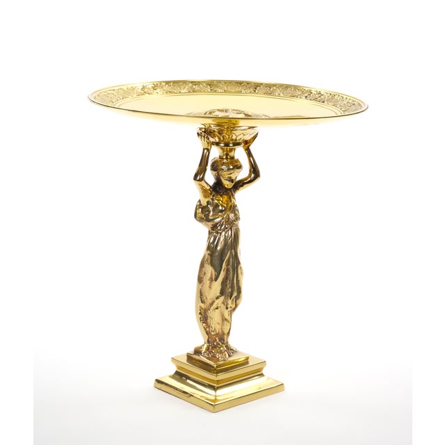 An elegant French 20th century brass figural centerpiece depicting a graceful classical maiden supporting a large circular...