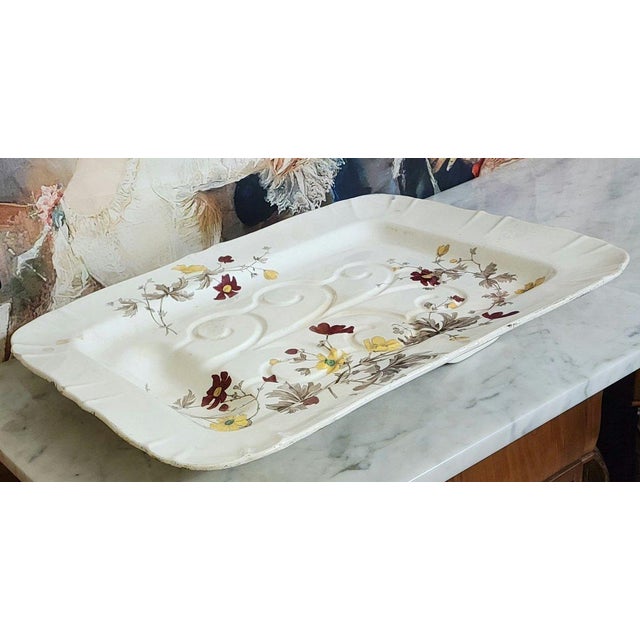 A very large rectangular platter with scalloped edges, made of fine cream-glazed earthenware, decorated with a painted...