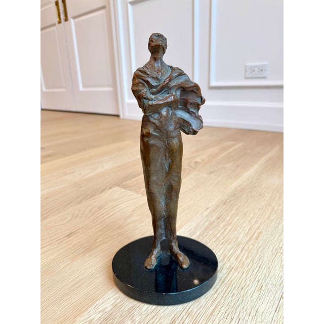 A striking limited-edition cast-bronze sculpture depicting an elongated female figure with her face dramatically lifted...
