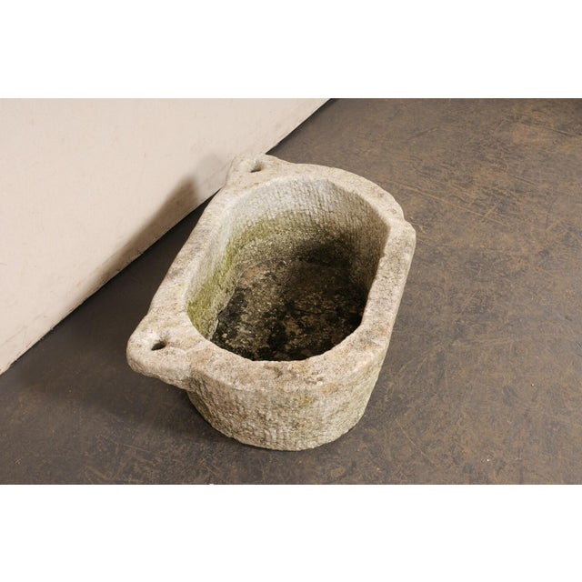 A Spanish hand-carved trough basin from the 19th century. This antique stone vessel from Spain has an oval-shaped basin...