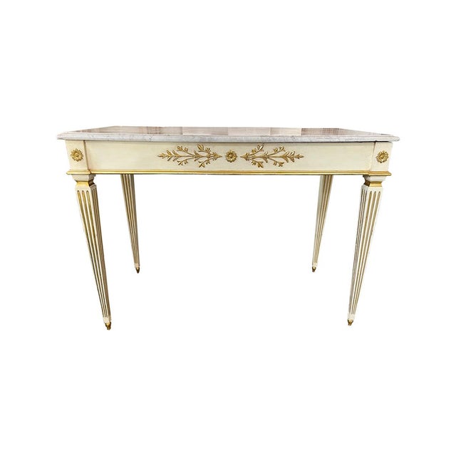 This pair of consoles is topped with Carrera marble. They are early 20th century and the frames are painted cream with...