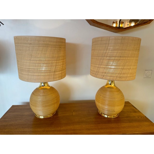 Mid-Century Modern pair of rattan wicker and brass table or bedside lamps. In the mood of Arpex International, Mario Lopez...