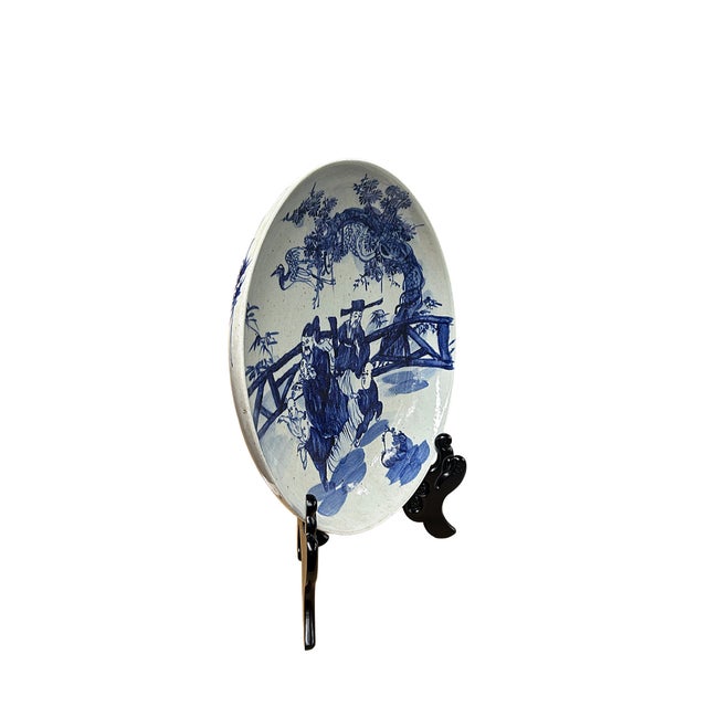 This large vintage ceramic charger features a vibrant underglaze blue hand-painted scene depicting figures and children...