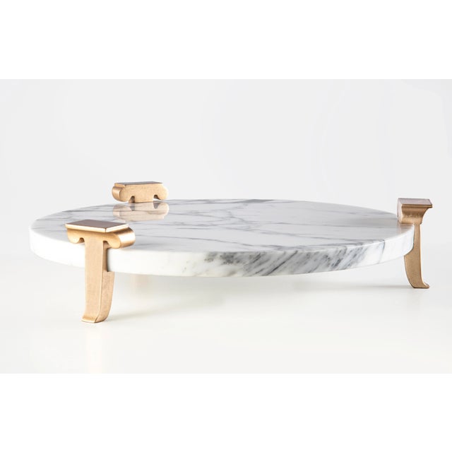 Handcrafted decorative circular Carrara marble tray with 3 gold -plated wooden legs.This elegant tray gives you a taste of...