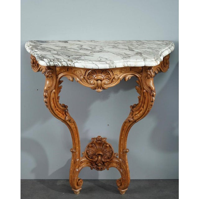 A pair of louis xv-inspired console tables crafted of marvelously carved natural elm wood. The naturalistic seashells and...