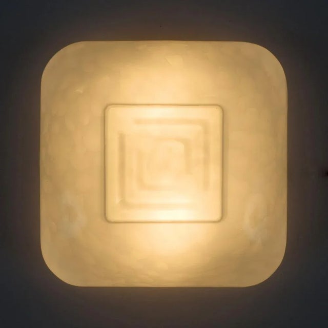 These wall lamps are formed by a metal base that holds a glass shade with a geometric design. When the lamp is lighted,...