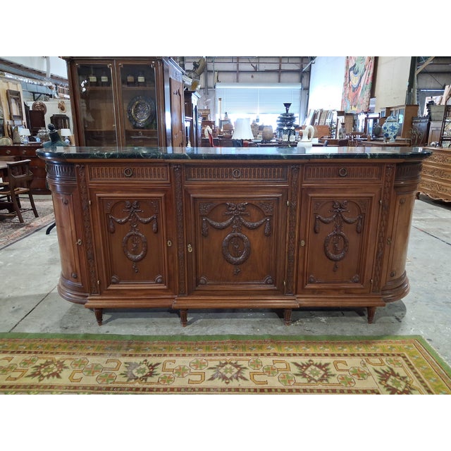 A refined French Louis XVI Revival dining room suite crafted in richly figured mahogany and crowned with original green...