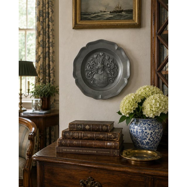 A handsome mid-20th-century European pewter wall plate centered by an elaborate heraldic coat of arms. The raised...