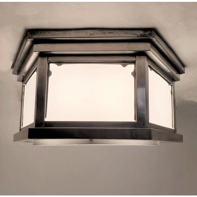 A hexagonal white glass flush mount fixture with stepped designed frame in a warm satin nickel over brass. The six sided...