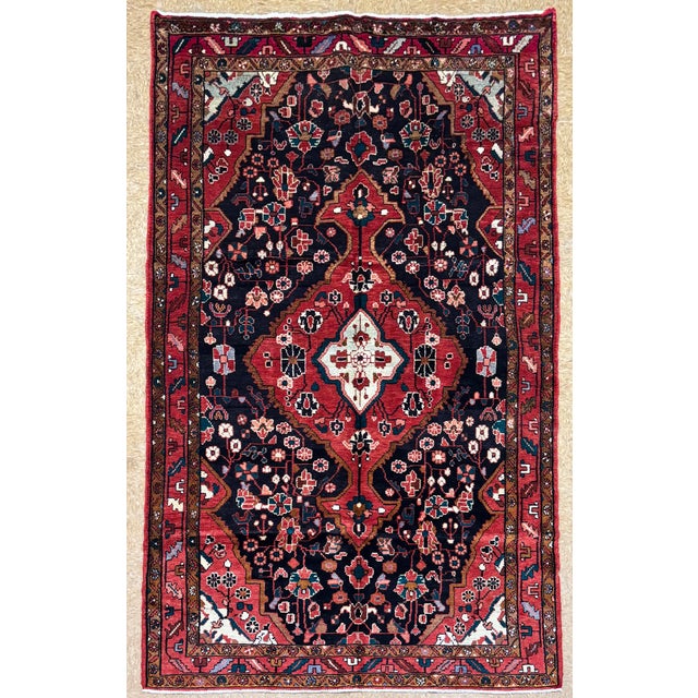 Hand-knotted rug from the Nahavand area of western Iran, featuring a large, elongated central medallion set within a deep...