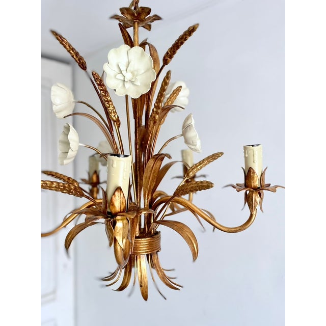 Gilt tole chandelier with five light arms, white tole florals and wheat motif detailing. Constructed of painted and gilt...