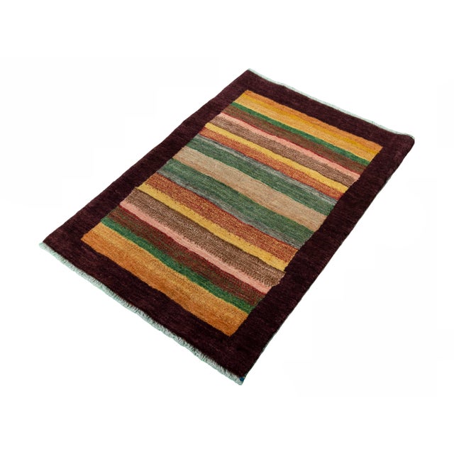 An authentic Gabbeh rug, hand-knotted by nomads from pure wool. This rug impresses with its bold striped composition in...