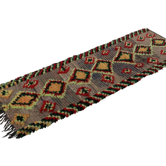 Hand-knotted in wool circa 1950-1960, this 3x8 vintage Moroccan rug with polychromatic geometric patterns and medallions,...